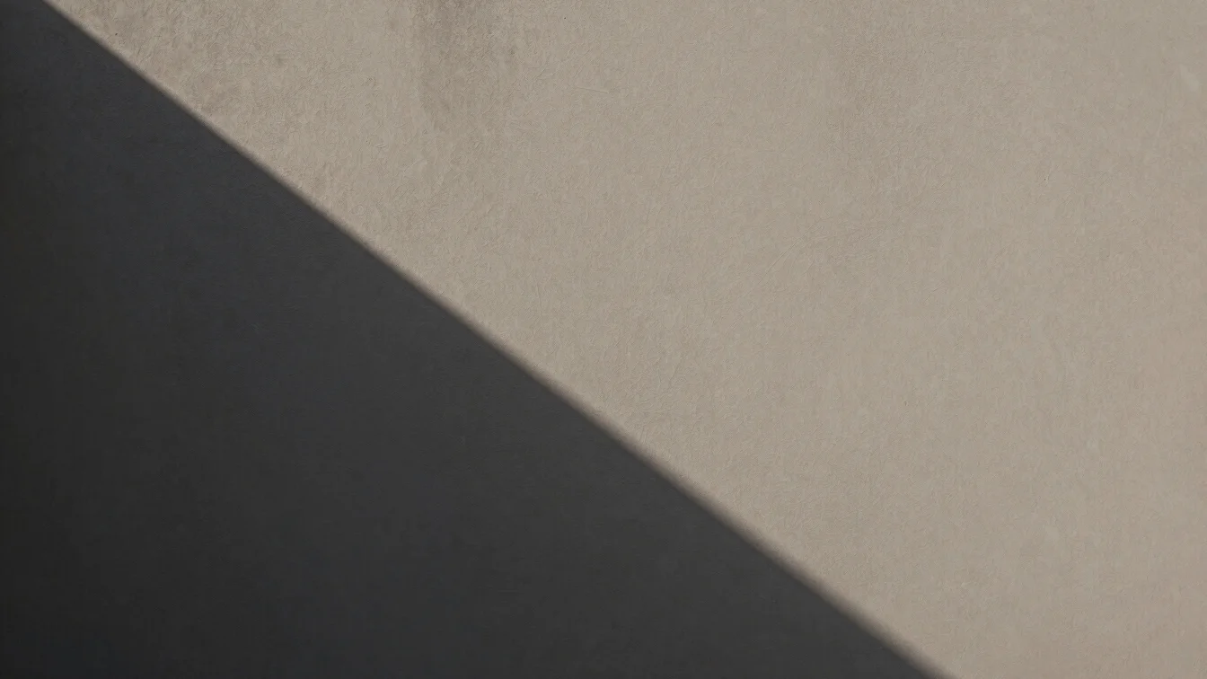 Geometric architectural shadows cast across textured monochromatic walls
